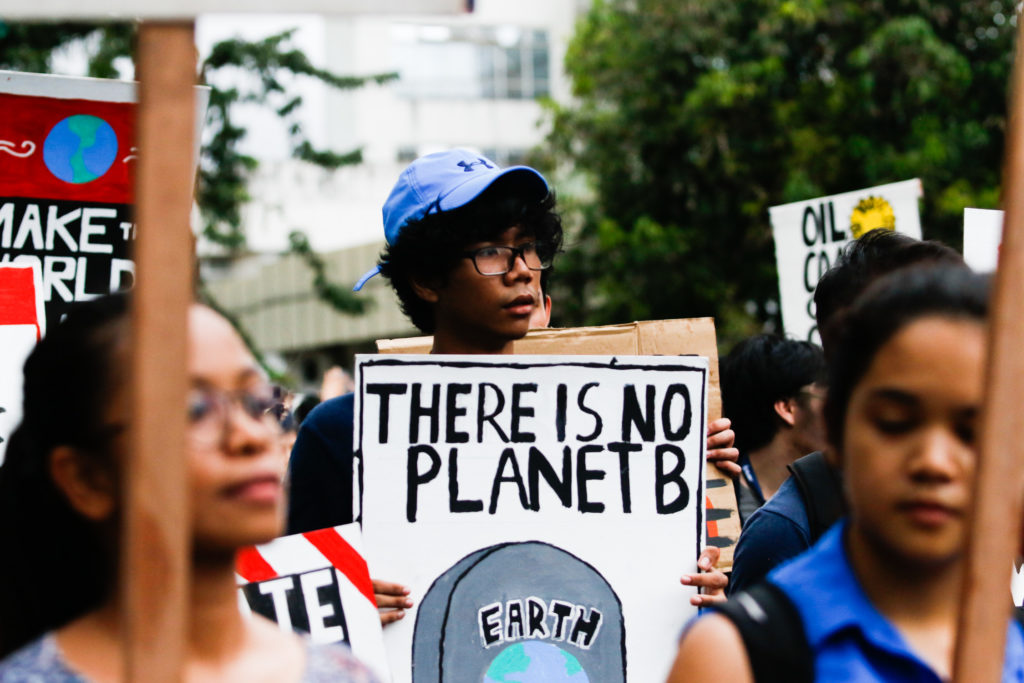 Photo of a young person at a protest holding a sign reading "THERE IS NO PLANET B". 600 youth, professionals and community leaders form a human earth banner at the University of the Philippines Diliman Quezon City, 20 September 2019. This is just one out of the 15 different climate strikes happening across the country.